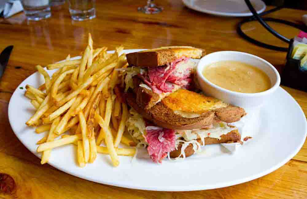 The Famous Reuben — grilled marble rye, sauerkraut, swiss cheese, house-smoked pastrami, with pub fries and dipping sauce